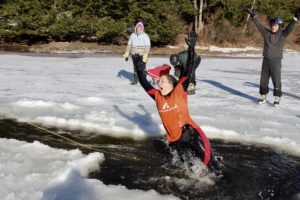 A woman leaps into water surrounded by ice