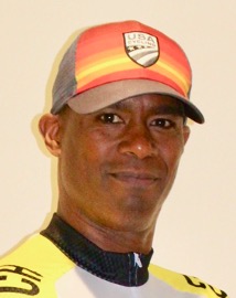 A man in an orange and helow hat looks at the camera