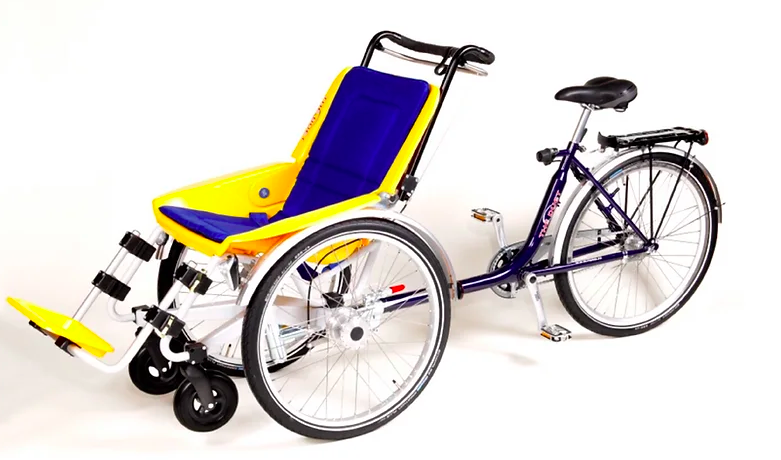 In front, a yellow and blue wheelchair with foot supports and velcro straps that can go over someone's body. Attached to the wheelchair, in back, a bicycle seat, wheel, and pedals.