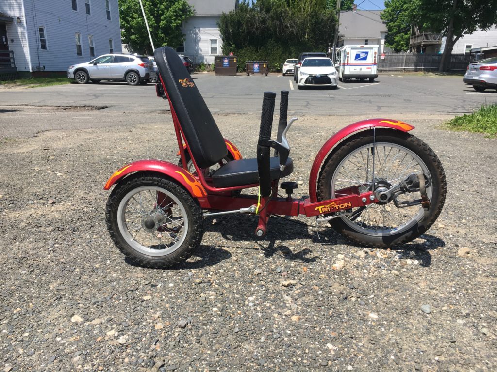Image shows a small red trike with one wheel in the front and 2 behind