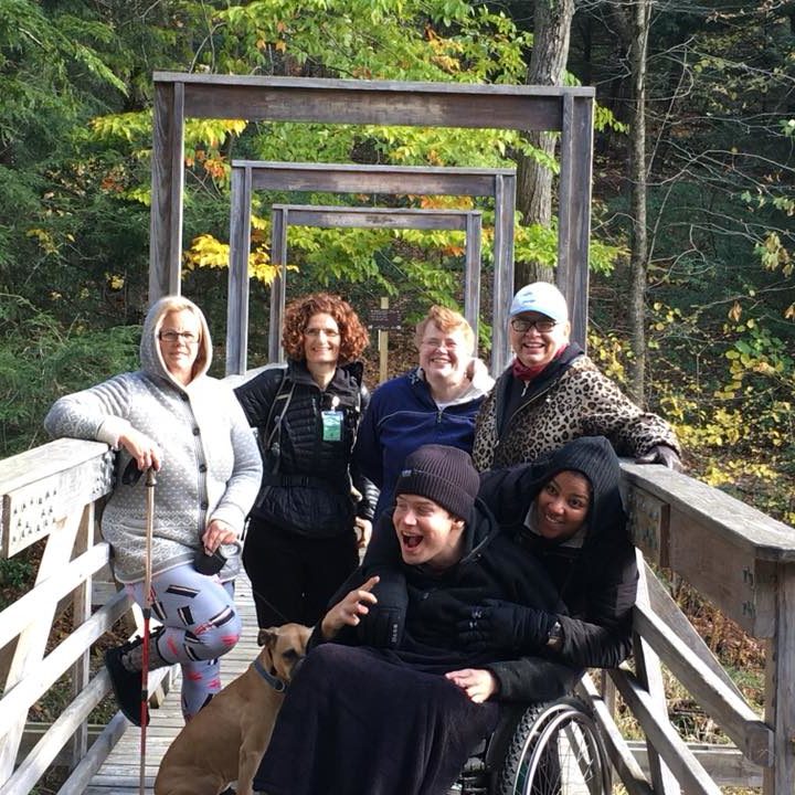 A group of people on a widden bridge look into the camera and are laughing