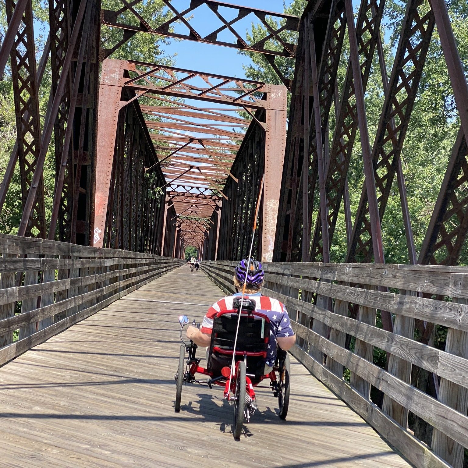 a person rides a recumbent trike away from the camera and across a former railroad bridge